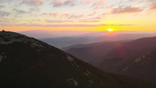 Aerial View of Foggy Evening Over High Peak with Dark Pine Forest Trees at Bright Sunset