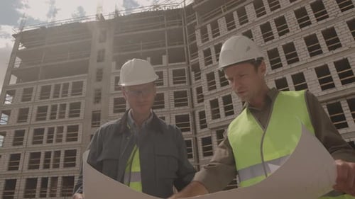 Construction Workers Review Blueprints at Sunny Building Site