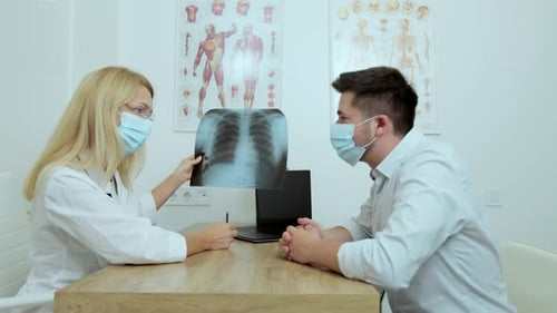 Doctor Reviews X-Ray With Patient in Office