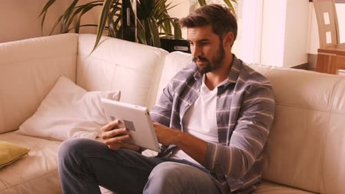 Man Using Tablet on Couch Indoors