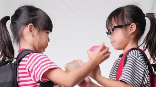 Young Girls Exchange Snacks Together Indoors