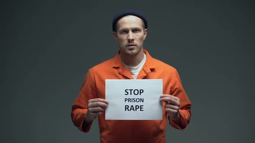 Caucasian Male Prisoner Holding Stop Prison Rape Sign in Cell, Sexual Harassment