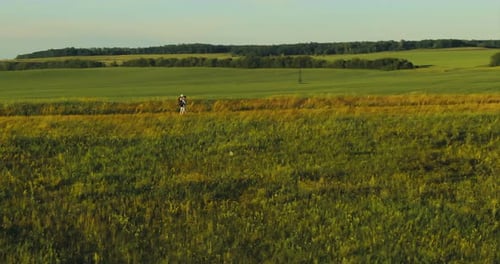 Aerial View of a Couple of Tourists Walking with Backpacks Through Meadows and Fields Hiking