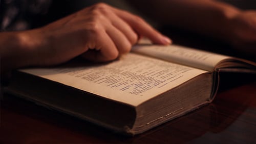 Hands Read Old Book on Table Close Up