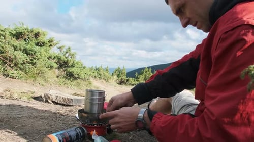 Man Prepares Food on Camping Stove in Nature