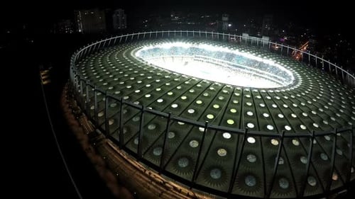 Crowded Tribunes at Brightly Illuminated Modern Stadium, Night Aerial View