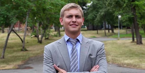 Smiling Man Standing in Park with Arms Crossed