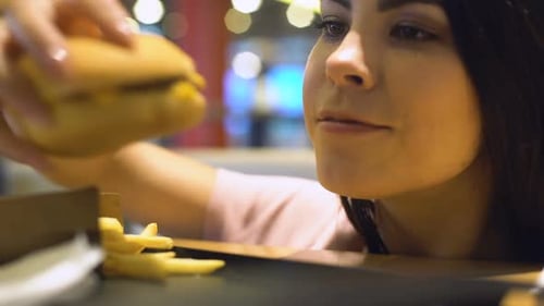 Jeune femme accro mangeant un gros burger nocif, manque de volonté, trop manger