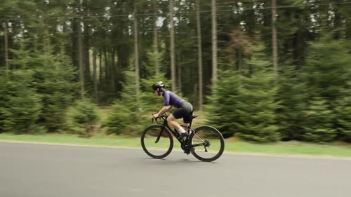 Female cyclist cycling bicycle on countryside road.