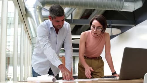 Business people discussing over blueprint in modern office