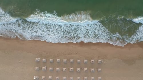 Sandy beach with straw sunshades and sunbeds