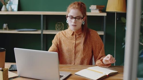 Young Woman Working on Laptop and Taking Notes