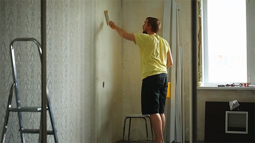 Man applies wallpaper glue in a bright room