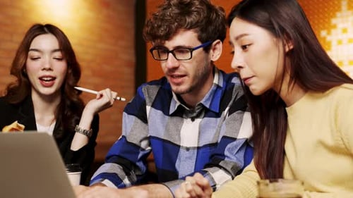 Young Adults Working Together on Laptop in Cafe