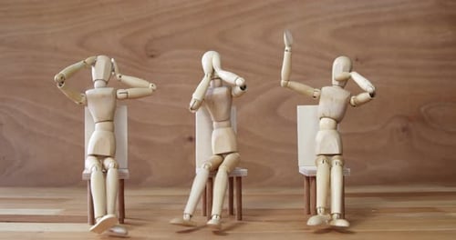 Three Wooden Figures Sitting in Chairs