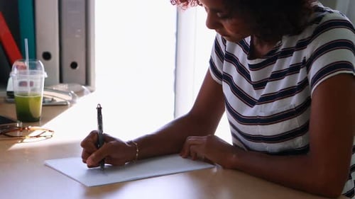 Female executive writing on paper at her desk