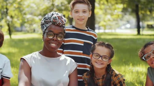 Portrait of Cheerful Multiethnic Kids and Teacher Posing for Camera in Park