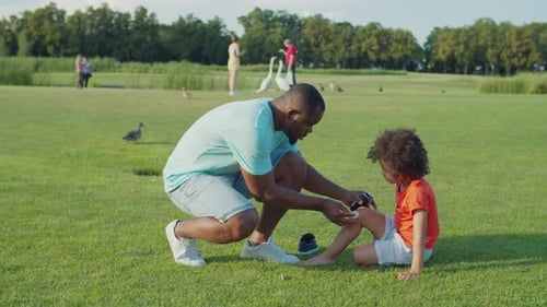 Father Applies Bandage to Child's Knee Outdoors