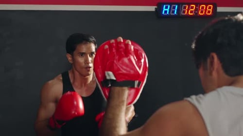 4K Asian man practicing boxing exercise with male sport trainer at gym.