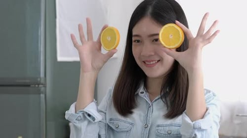 Woman Holding Orange Slices to Her Eyes