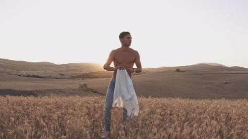 Brisa quente de verão em campos homem com camisa arremessada sobre ombros e céu ensolarado