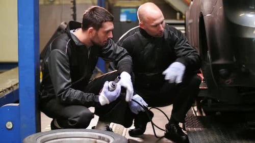 Auto Mechanics Changing Car Tires at Workshop