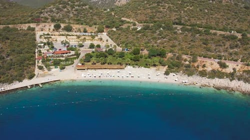 Tourists Swimming in the Azure Sea and Sunbathing on White Sand Beach on Mountains Background in Kas
