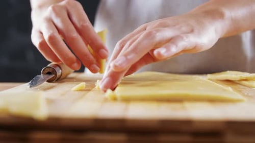 Femme tranchant la pâte sur une planche à découper