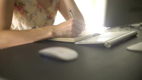 Woman Writing in Notebook at Desk Close Up