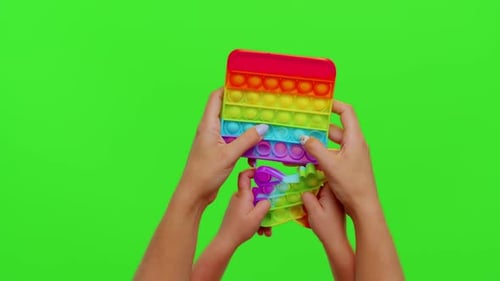 Hands of Woman and Kid Play Trendy Push Pop It Bubble Fidget Antistress Toys Game on Chroma Key