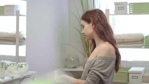 Young Woman Rinsing Mouth with Teeth Rinse Front Mirror in Bathroom