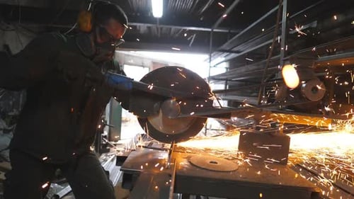 Man Cutting Metal with Safety Gear in Workshop