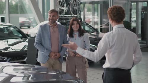 Salesman Talking to Couple Choosing Car in Dealership