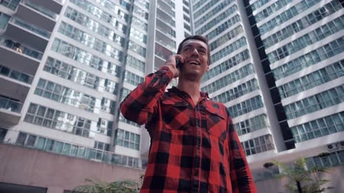 Young Man With Smartphone Standing Outdoors In City Making A Phone Call