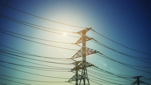 Electricity Pylons and Power Lines Pan Against Sunlight
