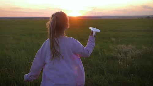 Young Girl Runs with Paper Airplane at Sunset