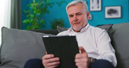 Man Using Tablet Device on Couch Indoors