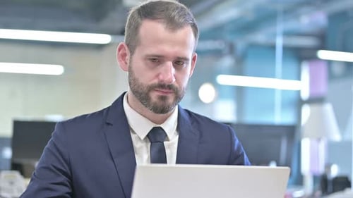 Focused Man Working on Laptop in Modern Office