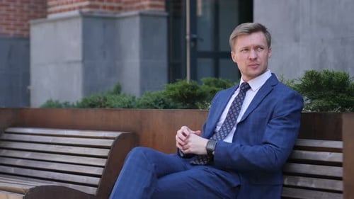 Waiting Businessman Watching Time on Smartwatch, Sitting Outside Office