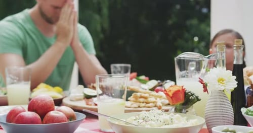 Family Holding Hands in Prayer at Meal