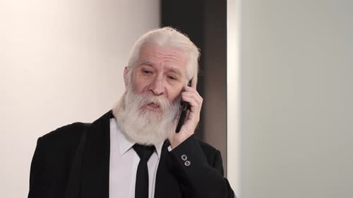 Reifer Mann im Anzug telefoniert im Büro