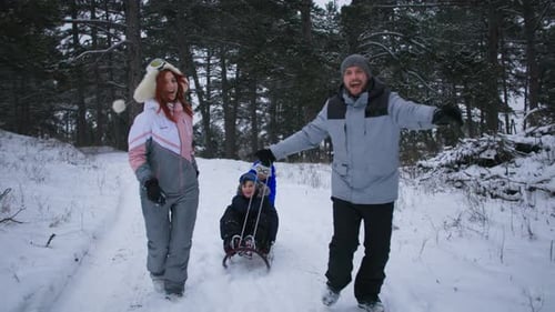 Happy Family Sledding Through a Snowy Winter Forest