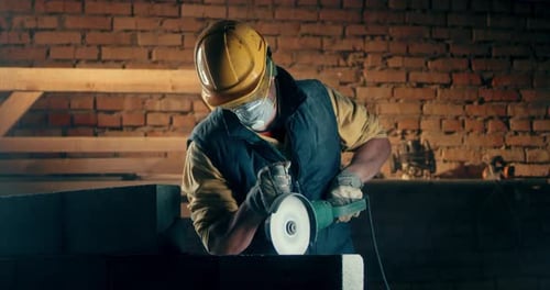 Male Builder in Respirator Cutting Wall