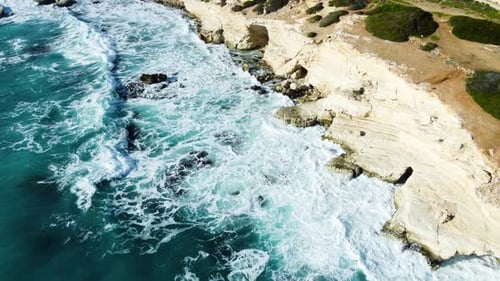 Sea Washes the Rocky Shore Above Aerial Shot Flying Over Coastline Cliffside with Blue Pure Water