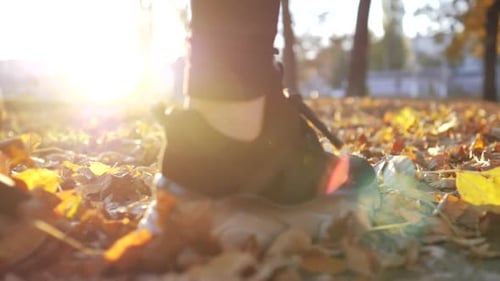 Feet Walking Across Autumn Leaves at Sunset