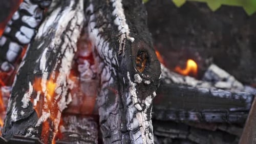 Lagerfeuer, Flamme und Brennholz. Im Feuer verbrannte Schwelhölzer, Nahaufnahme