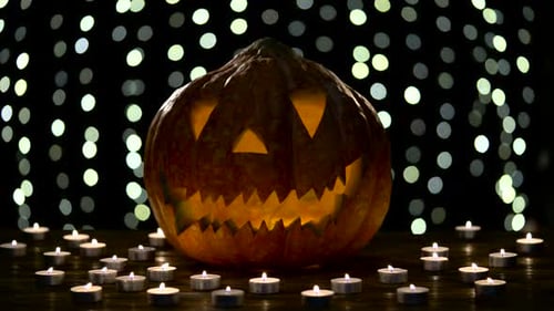Halloween-Kürbis-Lichter innen mit Flamme auf schwarzem Bokeh-Hintergrund mit brennenden Kerzen