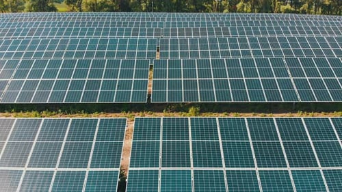 Luftaufnahme des Solarkraftwerks. Paneele stehen in einer Reihe auf der grünen Wiese.
Sommer