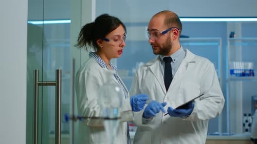 Scientists Collaborating, Analyzing Data on Tablet in Lab