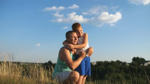 Father and Son Hugging in Grassy Field